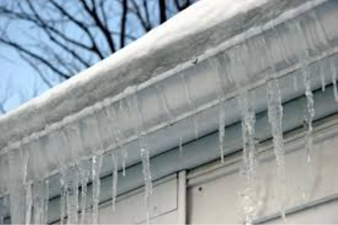 Ice dam built up along the gutter at the edge of a roof