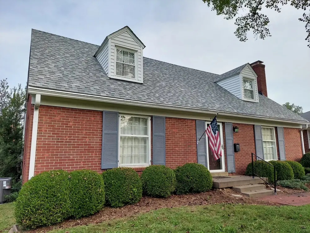 After: the same brick home with a new gray architectural shingle roof