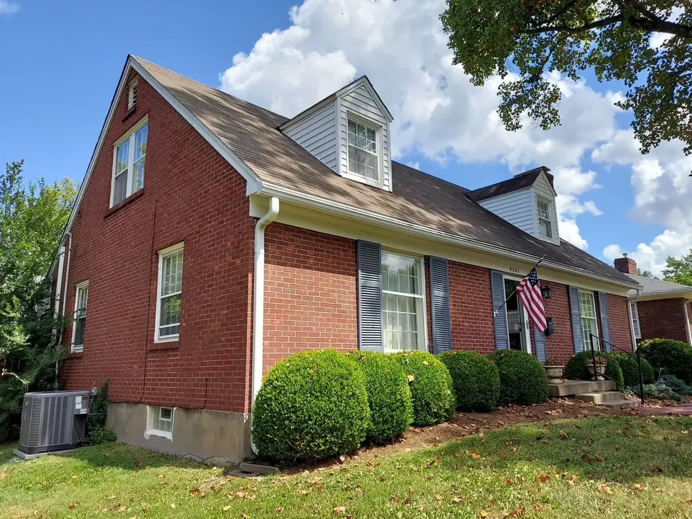Before: red brick Cape Cod home with its old worn brown shingle roof