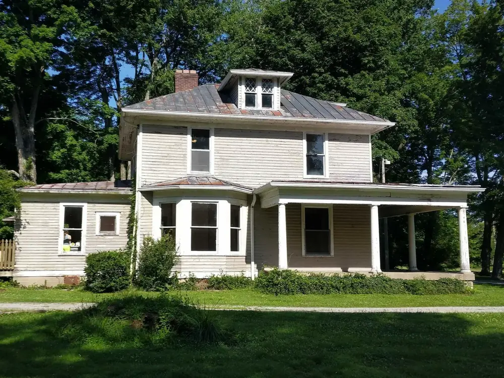 Before: two-story farmhouse with its old roof and faded siding