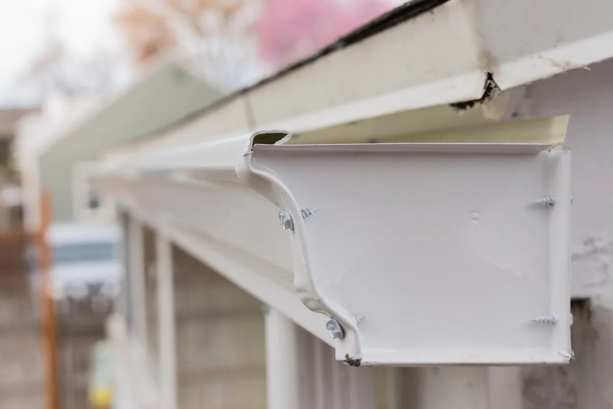 Damaged white gutter pulling away from a roofline