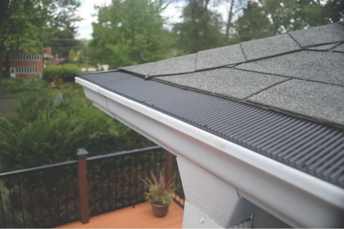 Gutter fitted with a gutter guard along a roofline, seen from a deck