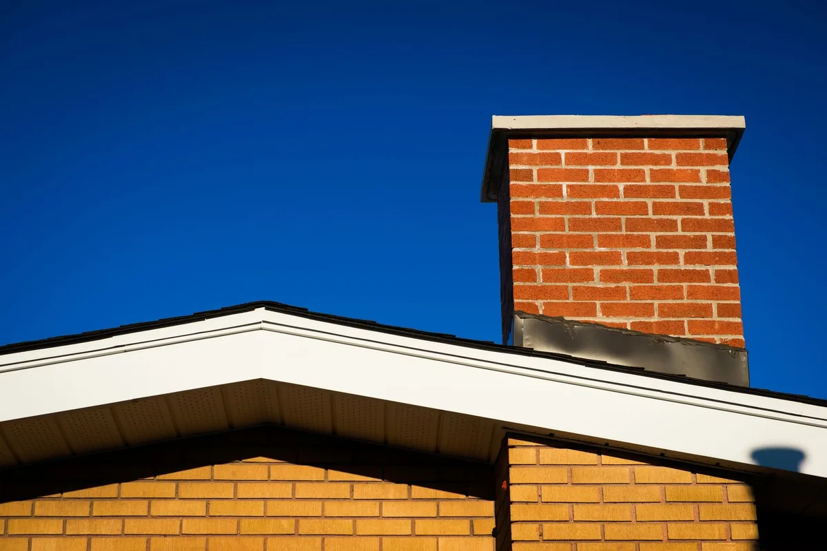 Brick chimney on a roof against a blue sky